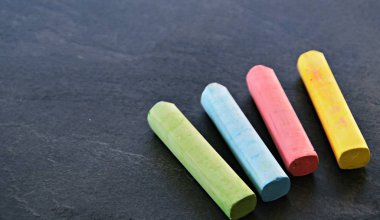 Farklı renkli tebeşir koyu mermer yüzey üzerinde yalan - renkli tebeşir ve metin veya diğer öğeler için yer ile bir arka plan olarak kavram 