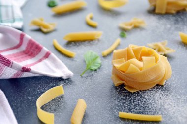 Erişte kelimesi unla kirlenmiş bir alanda, koyu mermer bir yüzeyde penne, farfalle ve fesleğen yaprakları gibi çeşitli makarnaçeşitleriyle birlikte yazılmıştır.