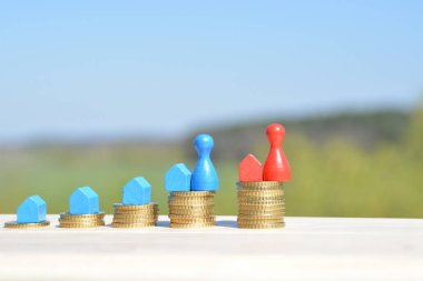  sikke farklı yüksekliklerde yığılmış, yükselen bir kulak sonuçlanan. Her yığını üzerinde evler ve bir oyun figürü finansmanı sembolize bir ev standları-metin için oda ile