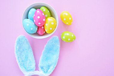 Üzerinde tavşan kulakları olan bir saç bandı pembe bir arka plan üzerinde, yanında beyaz noktalı Paskalya yumurtaları dolu bir eşarp - pastel renkleri ile Paskalya için renkler ile kavram -