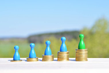  sikke farklı yüksekliklerde yığılmış, yükselen bir kulak sonuçlanan. Her yığını üzerinde evler ve bir oyun figürü finansmanı sembolize bir ev standları-metin için oda ile