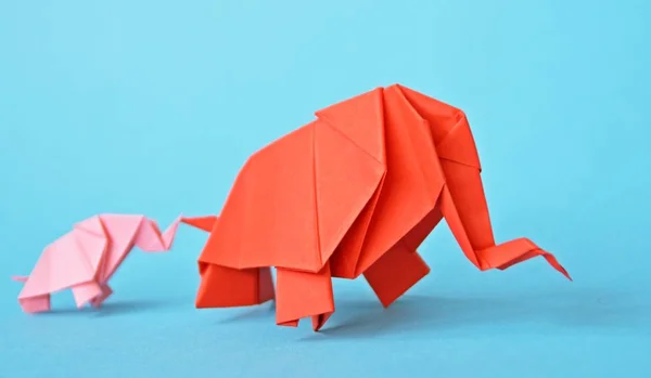 两头粉红色和红色的纸折叠大象站在蓝色背景上 概念与小小象和母象折叠根据折纸技术 — 图库照片