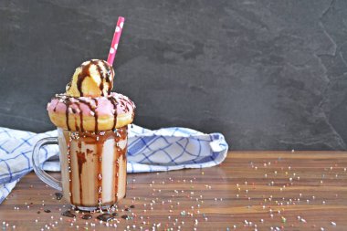Bir bardak çikolatalı süt, bir çörek ve dondurma bir kepçe ile yığılmış-kavramı tatlı milkshake ile 