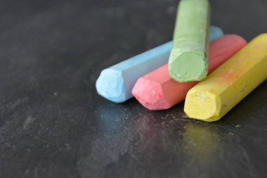 Farklı renkli tebeşir koyu mermer yüzey üzerinde yalan - renkli tebeşir ve metin veya diğer öğeler için yer ile bir arka plan olarak kavram 