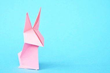 Pastel kağıt tan katlanmış bir origami tavşan mavi bir taban üzerinde duruyor - origami ile kavram ve Paskalya için metin veya diğer unsurlar için yer