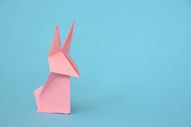Pastel kağıt tan katlanmış bir origami tavşan mavi bir taban üzerinde duruyor - origami ile kavram ve Paskalya için metin veya diğer unsurlar için yer