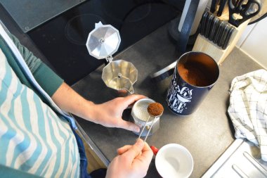 20'li yaşlarda bir adam espresso makinesiyle kahve hazırlar. 