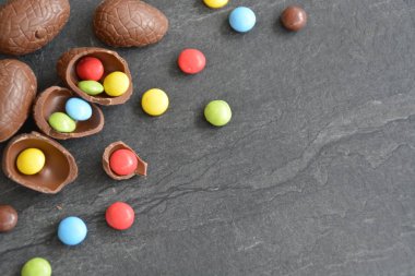 Birkaç çikolata yumurta karanlık bir mermer yüzey, bazıları kırılmış, yumurta ve yanında renkli çikolata-kavramı Paskalya tatlılar ve metin veya diğer unsurlar için boşluk 