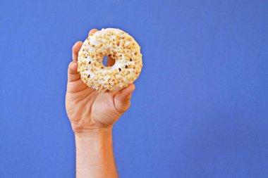 Bir el Çikolata buzlanma ile bir donut tutar yukarı. Arka plan renkli ve metin veya diğer unsurlar için oda bırakır
