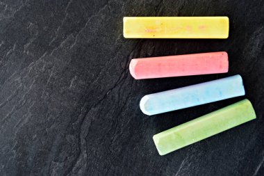 Farklı renkli tebeşir koyu mermer yüzey üzerinde yalan - renkli tebeşir ve metin veya diğer öğeler için yer ile bir arka plan olarak kavram 