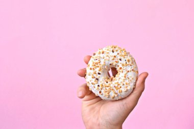 Bir el Çikolata buzlanma ile bir donut tutar yukarı. Arka plan renkli ve metin veya diğer unsurlar için oda bırakır