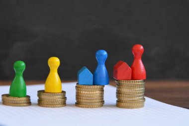  sikke farklı yüksekliklerde yığılmış, yükselen bir kulak sonuçlanan. Her yığını üzerinde evler ve bir oyun figürü finansmanı sembolize bir ev standları-metin için oda ile