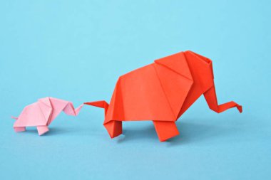 Mavi bir arka plan üzerinde pembe ve kırmızı stand iki kağıt katlanmış filler - küçük bir bebek fil ve origami tekniğine göre katlanmış bir anne fil ile kavram