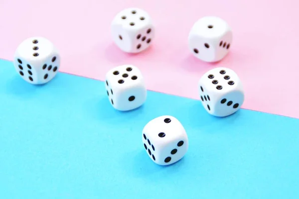Two dice with opposite color play - one dice is blue and stands on pink background, the other red on blue background - concept with colors and dice
