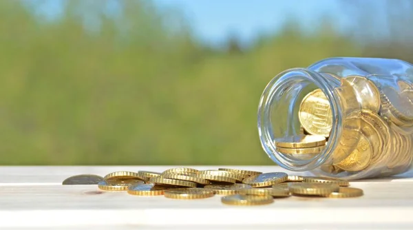 A jar full of savings stands on a space next to a purse of saved coins that pile up to form a tall tower - saving concept with room for text or other items