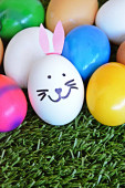 A fehér tojás, a nyúl arca festett, és fülek ragasztott rá-koncepció Húsvét a hely a szöveg 