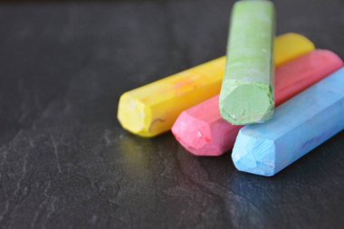 Farklı renkli tebeşir koyu mermer yüzey üzerinde yalan - renkli tebeşir ve metin veya diğer öğeler için yer ile bir arka plan olarak kavram 