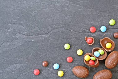 Birkaç çikolata yumurta karanlık bir mermer yüzey, bazıları kırılmış, yumurta ve yanında renkli çikolata-kavramı Paskalya tatlılar ve metin veya diğer unsurlar için boşluk 