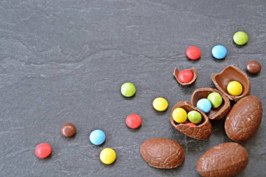 Birkaç çikolata yumurta karanlık bir mermer yüzey, bazıları kırılmış, yumurta ve yanında renkli çikolata-kavramı Paskalya tatlılar ve metin veya diğer unsurlar için boşluk 