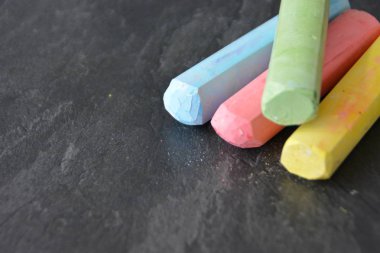 Farklı renkli tebeşir koyu mermer yüzey üzerinde yalan - renkli tebeşir ve metin veya diğer öğeler için yer ile bir arka plan olarak kavram 