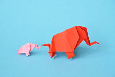 Mavi bir arka plan üzerinde pembe ve kırmızı stand iki kağıt katlanmış filler - küçük bir bebek fil ve origami tekniğine göre katlanmış bir anne fil ile kavram
