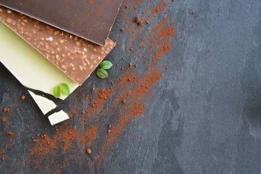 Üç koyu çikolata, fındık ve beyaz çikolata koyu mermer yüzey üzerinde yalan - metin veya diğer unsurlar için oda ile karanlık bir yüzey üzerinde çikolata