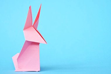 Pastel kağıt tan katlanmış bir origami tavşan mavi bir taban üzerinde duruyor - origami ile kavram ve Paskalya için metin veya diğer unsurlar için yer