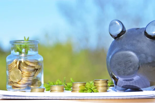 A jar full of savings stands on a space next to a purse of saved coins that pile up to form a tall tower - saving concept with room for text or other items