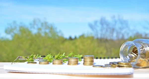 A jar full of savings stands on a space next to a purse of saved coins that pile up to form a tall tower - saving concept with room for text or other items