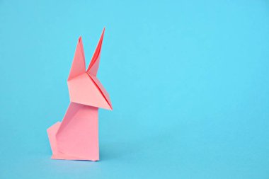 Pastel kağıt tan katlanmış bir origami tavşan mavi bir taban üzerinde duruyor - origami ile kavram ve Paskalya için metin veya diğer unsurlar için yer