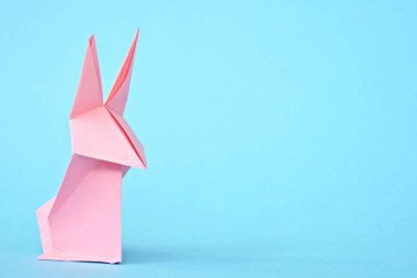 Pastel kağıt tan katlanmış bir origami tavşan mavi bir taban üzerinde duruyor - origami ile kavram ve Paskalya için metin veya diğer unsurlar için yer