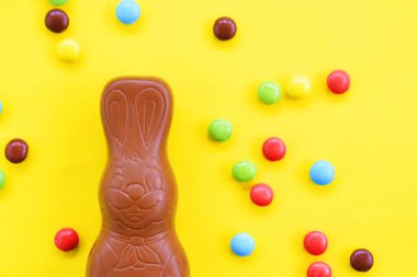 Bir Paskalya tavşanı dışında renkli çikolata parçaları ile çikolata yapılmış tek amaçlı bir yüzey üzerinde yatıyor - renkli bir yüzeyüzerinde tatlılar paskalya