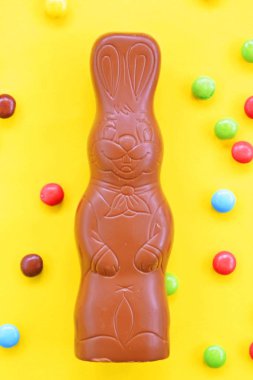 Bir Paskalya tavşanı dışında renkli çikolata parçaları ile çikolata yapılmış tek amaçlı bir yüzey üzerinde yatıyor - renkli bir yüzeyüzerinde tatlılar paskalya