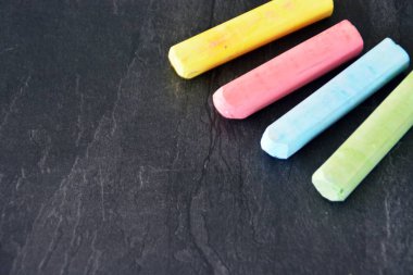 Farklı renkli tebeşir koyu mermer yüzey üzerinde yalan - renkli tebeşir ve metin veya diğer öğeler için yer ile bir arka plan olarak kavram 