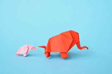 Mavi bir arka plan üzerinde pembe ve kırmızı stand iki kağıt katlanmış filler - küçük bir bebek fil ve origami tekniğine göre katlanmış bir anne fil ile kavram