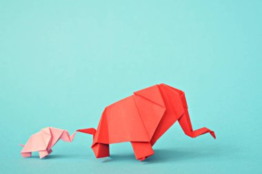 Mavi bir arka plan üzerinde pembe ve kırmızı stand iki kağıt katlanmış filler - küçük bir bebek fil ve origami tekniğine göre katlanmış bir anne fil ile kavram