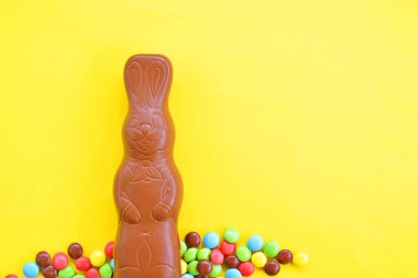 Bir Paskalya tavşanı dışında renkli çikolata parçaları ile çikolata yapılmış tek amaçlı bir yüzey üzerinde yatıyor - renkli bir yüzeyüzerinde tatlılar paskalya