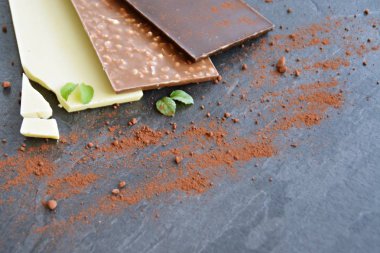 Üç koyu çikolata, fındık ve beyaz çikolata koyu mermer yüzey üzerinde yalan - metin veya diğer unsurlar için oda ile karanlık bir yüzey üzerinde çikolata