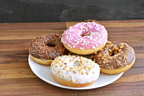 Auf Einer Holzoberfläche Liegt Ein Teller Mit Verschiedenen Donuts Die — Stockfoto