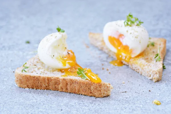 On a freshly roasted whole wheat toast is a boiled egg with soft egg yolk, which flows out of the egg. On the egg is cress and salt and pepper