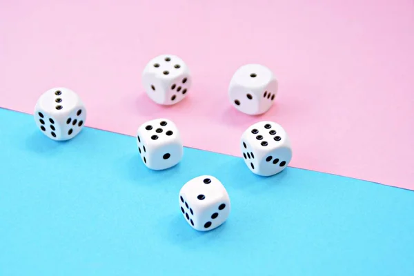 Two dice with opposite color play - one dice is blue and stands on pink background, the other red on blue background - concept with colors and dice