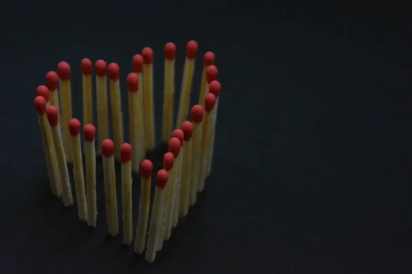 Matches stick in a dark area and have the shape of a heart as they burn off with a bright flame - a concept for blazing love and hot desire