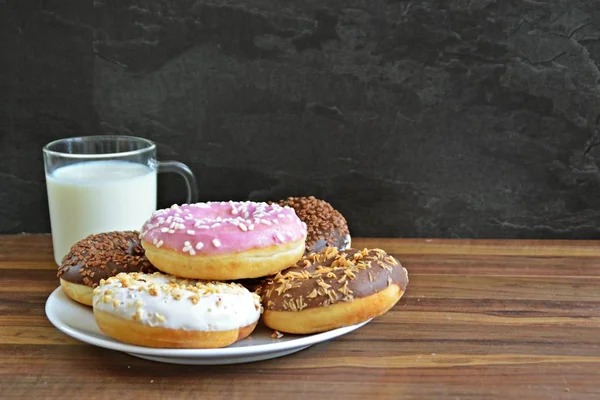 Auf Einer Holzoberfläche Liegt Ein Teller Mit Verschiedenen Donuts Die — Stockfoto