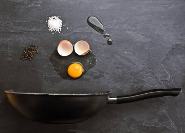 Bir tava açık bir yumurta, tuz ve biber ve ayçiçek yağı bir damla yüzen yukarıda bir yüzey üzerinde yatıyor - kavram soyut bir sunum ile yumurta kızartmak için