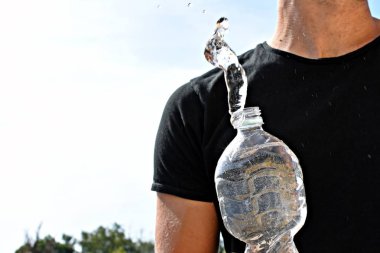 Siyah gömlekli bir adam elinde su ile plastik bir şişe tutar, hangi su bir ivme uçar - yaz aylarında su ile soğutma ferahlatıcı için kavram