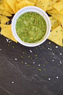 Koyu mermer bir yüzeyde soğan ve birçok baharat ile ev yapımı guacamole bir kase yanında tuz ile nachos bir yığın var - metin için alan ile lezzetli atıştırmalık