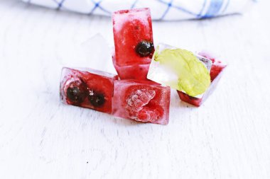 Yaz aylarında serinletici soğutma olarak, hafif ahşap bir yüzey üzerinde yalan içinde donan çeşitli çilek ile buz küpleri - Buz küpleri lezzetli ve organik çilek