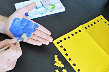 Bir kişi bulutlu bir gökyüzü önünde elini tutuyor , el sarı kağıt yıldız ile Avrupa Birliği renkleri ile boyanmıştır - kavram ab ve oy özgürlüğü kutlamak için