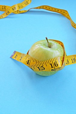 Sarı bir ölçüm bandı beyaz bir arka plan önünde, bir elma etrafında sarılmış oldu - diyet ve metin veya diğer unsurlar için alan ile sağlık nedeniyle zayıflama kavramı 