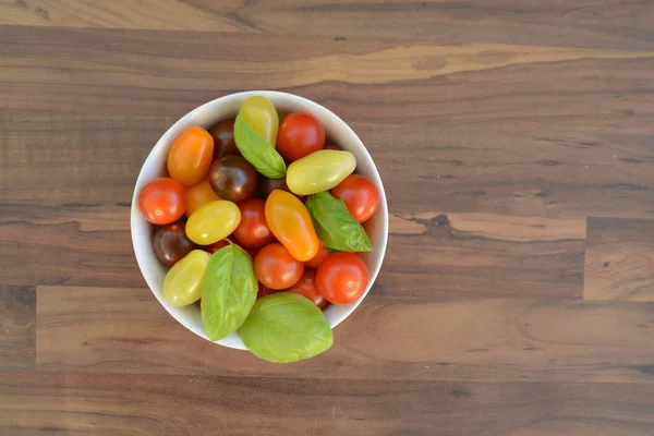 Different types of tomatoes in different colors and basil - concept with fresh and healthy different tomatoes, with space for text for other elements